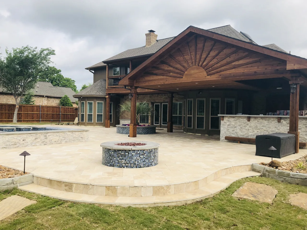 Light patio surface connecting a covered gathering space and a circular fire feature