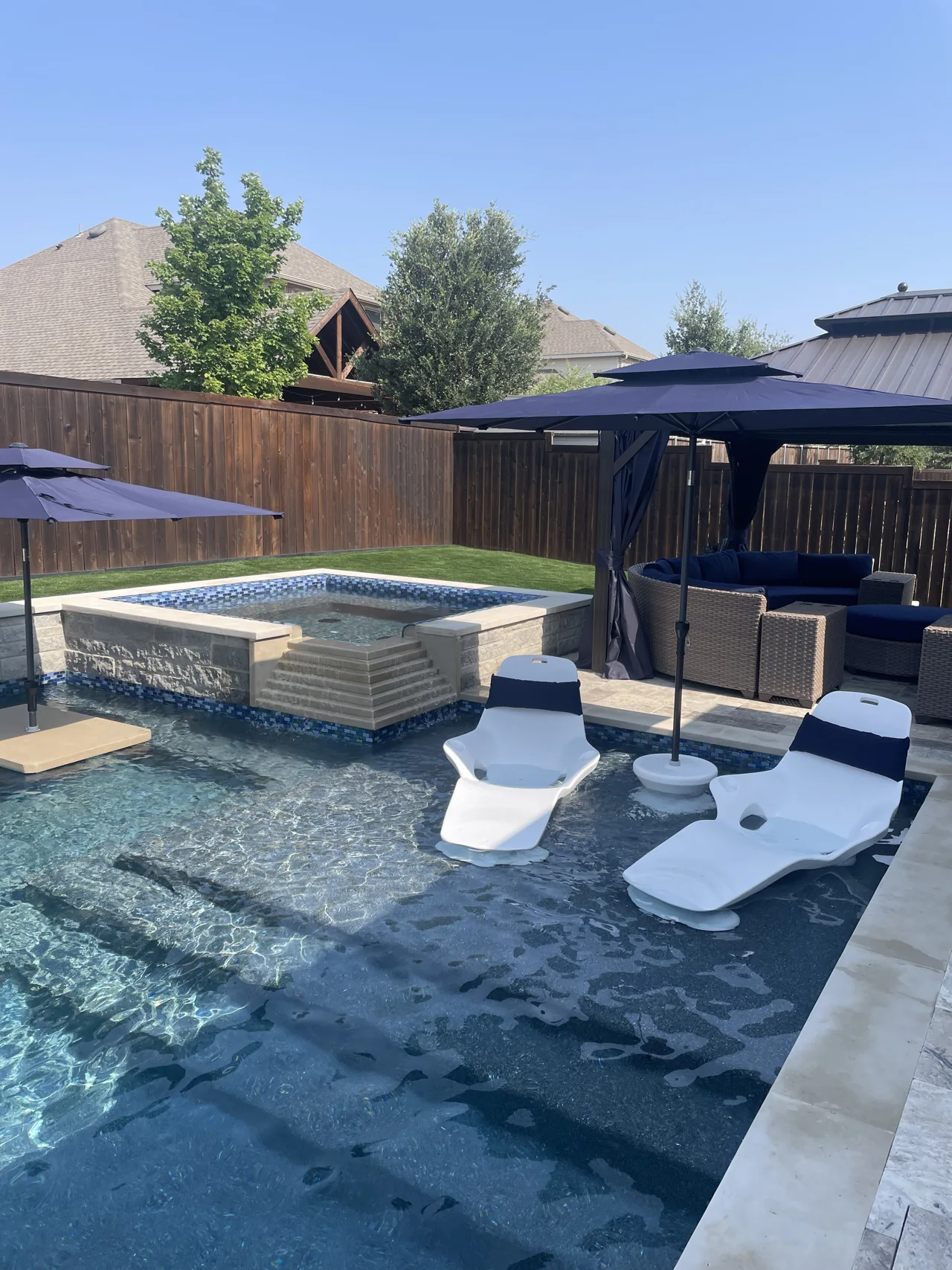 Poolside lounge chairs on a shallow ledge beside a raised spa