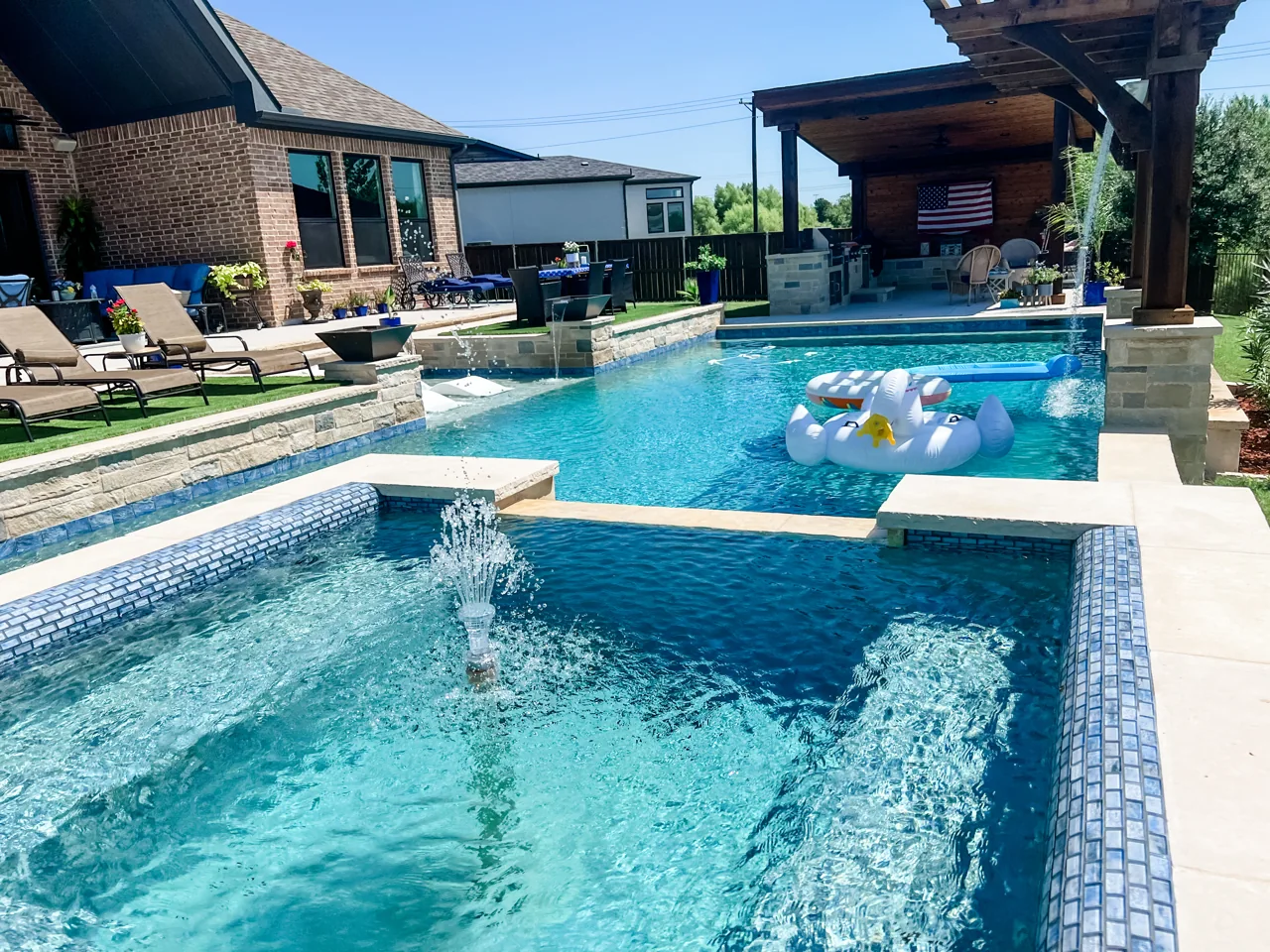 Pool and raised spa with light coping, blue water and a covered outdoor space